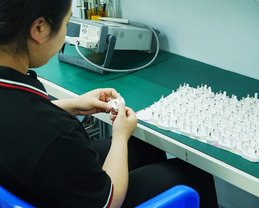 Worker checking interchangeable plug adapters for the CB ultra-thin GaN chargers